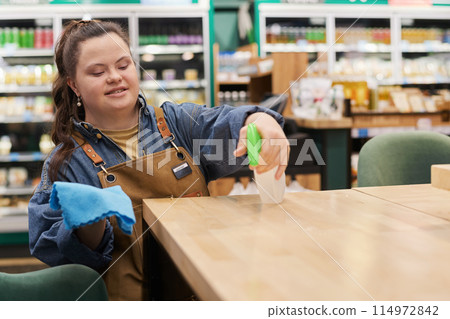 Waist up portrait of smiling young woman with disability working in supermarket and sanitizing tables in cafe area copy space Waist up portrait of smiling young woman with disability working in supermarket and sanitizing tables in cafe area copy space 114972842