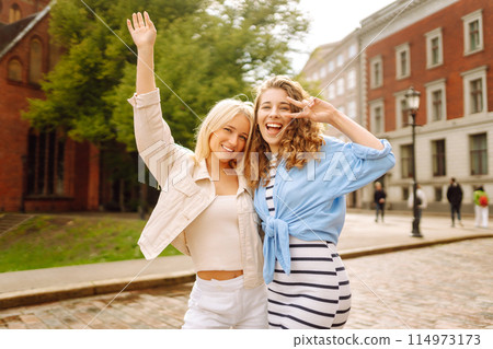 Two young women walk along the city streets. Concept of lifestyle, fashion, travel. 114973173