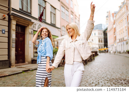 Two young women walk along the city streets. Concept of lifestyle, fashion, travel. 114973184