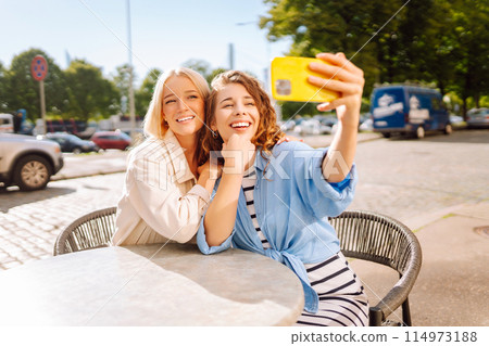 Beautiful woman friends using smartphone selfie together. Fashion, beauty, blogging, tourism. Beautiful woman friends using smartphone selfie together. Fashion, beauty, blogging, tourism. 114973188