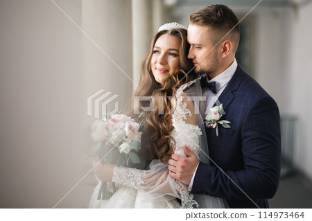 Romantic wedding moment, couple of newlyweds smiling portrait, bride and groom hugging 114973464