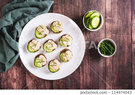 Delicious sandwiches on rye bread with cucumber, capelin caviar and green onions top view 114974043