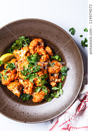 Baked cauliflower in tomato sauce with herbs, white background. 114974072