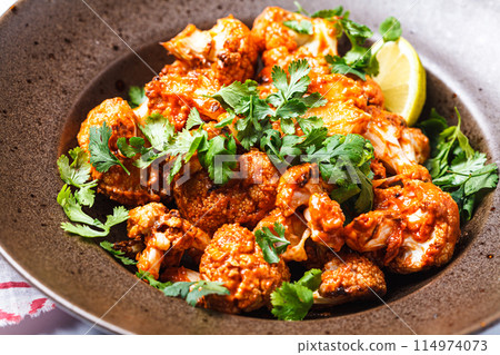 Baked cauliflower in tomato sauce with herbs, white background. 114974073