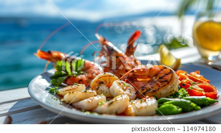 Grilled seafood plate with a mix of shrimp and scallops served by the sea, capturing a taste of the ocean breeze. 114974180