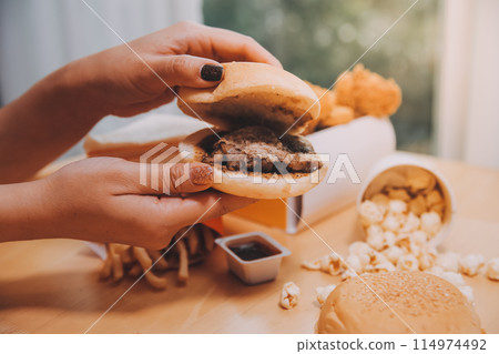 fast food, people and unhealthy eating concept - close up of woman hands holding hamburger or cheeseburger fast food, people and unhealthy eating concept - close up of woman hands holding hamburger or cheeseburger 114974492