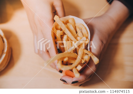 Asian woman holding french fries and eating happily in restaurant 114974515