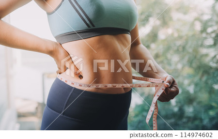 fat woman, fat belly, chubby, obese woman hand holding excessive belly fat with measure tape, woman diet lifestyle concept 114974602