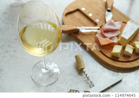 A glass of cold white wine and a cheese platter with snacks on a white background A glass of cold white wine and a cheese platter with snacks on a white background 114974645