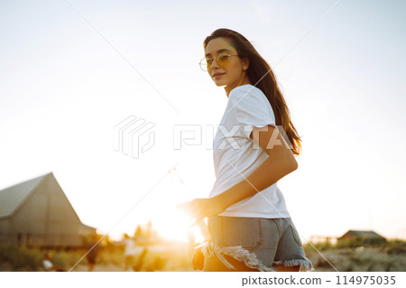 Pretty girl drinking beer at the beach at sunset. Young woman enjoying on beach holiday. Summertime 114975035
