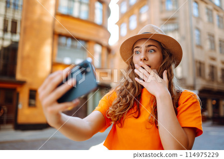 Selfie time. Woman on vacation having fun driving electric scooter through city. Active life concept 114975229