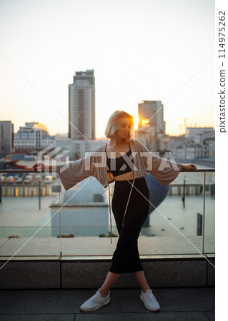 Beautiful woman standing on roof, feel happy at sunset. Freedom. Lifestyle, relaxation concept. 114975262