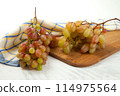 Cutting board with bunch of organic pink grapes on white wooden background.. 114975564