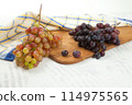 Cutting board with bunches of organic pink and dark blue grapes on white wooden background.. 114975565