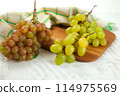 Cutting board with bunch of organic green and pink grapes on white wooden background.. 114975569