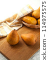 Cutting board with pears, wicker basket and yellow kitchen towel on white wooden background.. 114975575