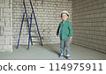 a little boy in a white helmet with documents in his hands 114975911