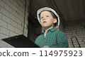 A little boy with a tablet with documents is standing on a construction site 114975923
