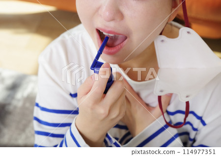 Woman spraying medicine into her mouth 114977351