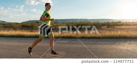 Triathlete in professional gear running early in the morning, preparing for a marathon, dedication to sport and readiness to take on the challenges of a marathon. Triathlete in professional gear running early in the morning, preparing for a marathon, dedication to sport and readiness to take on the challenges of a marathon. 114977731