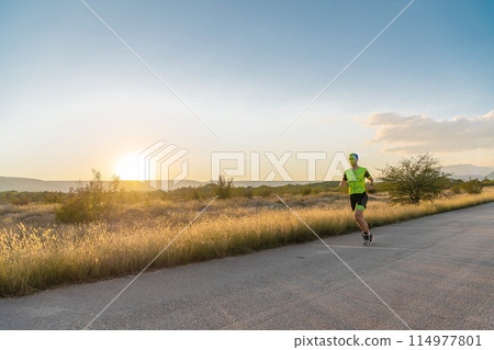 Triathlete in professional gear running early in the morning, preparing for a marathon, dedication to sport and readiness to take on the challenges of a marathon.  114977801