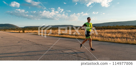 Triathlete in professional gear running early in the morning, preparing for a marathon, dedication to sport and readiness to take on the challenges of a marathon.  114977806