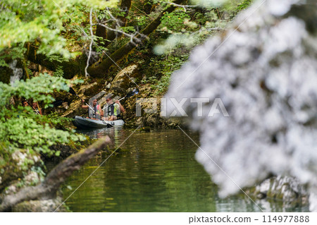 A young couple enjoying an idyllic kayak ride in the middle of a beautiful river surrounded by forest greenery 114977888