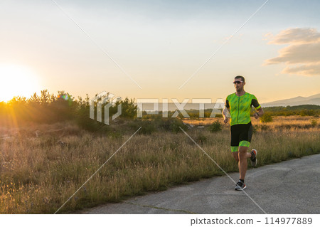 Triathlete in professional gear running early in the morning, preparing for a marathon, dedication to sport and readiness to take on the challenges of a marathon.  114977889
