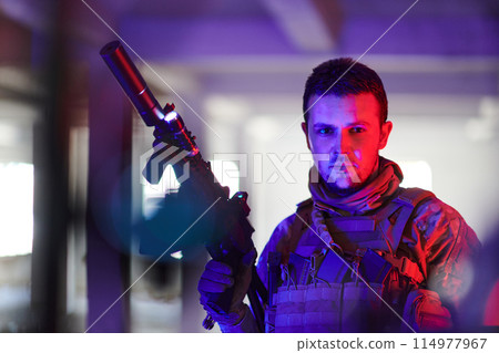 A professional soldier undertakes a perilous mission in an abandoned building illuminated by neon blue and purple lights A professional soldier undertakes a perilous mission in an abandoned building illuminated by neon blue and purple lights 114977967