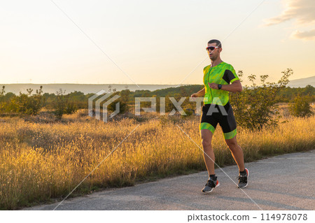 Triathlete in professional gear running early in the morning, preparing for a marathon, dedication to sport and readiness to take on the challenges of a marathon. Triathlete in professional gear running early in the morning, preparing for a marathon, dedication to sport and readiness to take on the challenges of a marathon. 114978078