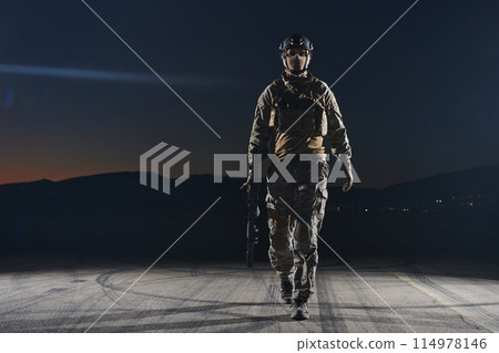 A professional soldier in full military gear striding through the dark night as he embarks on a perilous military mission 114978146