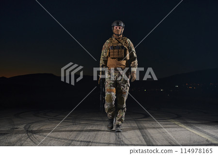 A professional soldier in full military gear striding through the dark night as he embarks on a perilous military mission A professional soldier in full military gear striding through the dark night as he embarks on a perilous military mission 114978165