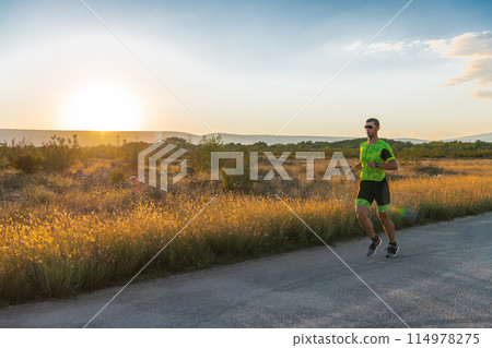 Triathlete in professional gear running early in the morning, preparing for a marathon, dedication to sport and readiness to take on the challenges of a marathon.  114978275