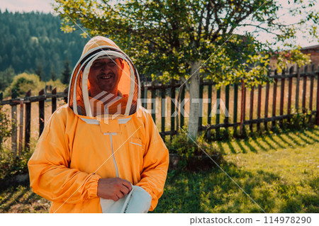 Beekeeper put on a protective beekeeping suit and preparing to enter the apiary 114978290