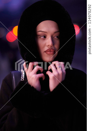 Muslim woman walking on an urban city street on a cold winter night wearing hijab 114978292