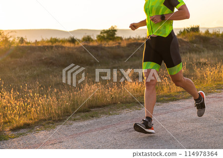 Triathlete in professional gear running early in the morning, preparing for a marathon, dedication to sport and readiness to take on the challenges of a marathon.  114978364