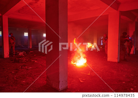 A group of professional soldiers bravely executes a dangerous rescue mission, surrounded by fire in a perilous building. 114978435