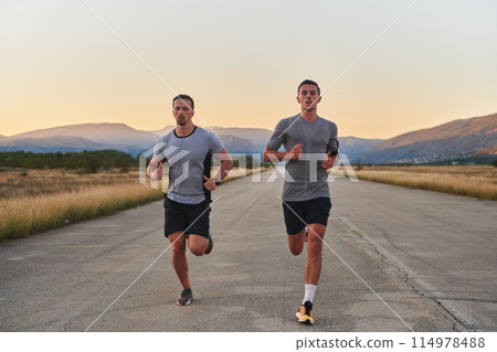 Group of handsome men running together in the early morning glow of the sunrise, embodying the essence of fitness, vitality, and the invigorating joy of embracing nature's tranquility during their Group of handsome men running together in the early morning glow of the sunrise, embodying the essence of fitness, vitality, and the invigorating joy of embracing nature's tranquility during their 114978488