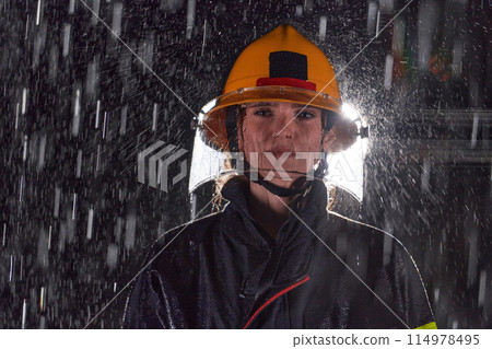 A determined female firefighter in a professional uniform striding through the dangerous, rainy night on a daring rescue mission, showcasing her unwavering bravery and commitment to saving lives. A determined female firefighter in a professional uniform striding through the dangerous, rainy night on a daring rescue mission, showcasing her unwavering bravery and commitment to saving lives. 114978495