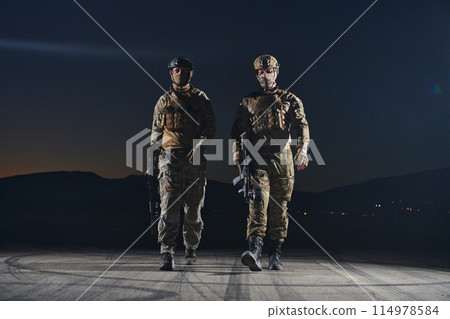 Two professional soldiers marching through the dark of night on a dangerous mission, epitomizing their unwavering bravery, unwavering teamwork, and the high-stakes intensity of their specialized Two professional soldiers marching through the dark of night on a dangerous mission, epitomizing their unwavering bravery, unwavering teamwork, and the high-stakes intensity of their specialized 114978584