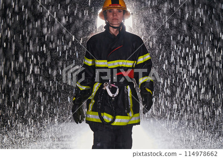 A determined female firefighter in a professional uniform striding through the dangerous, rainy night on a daring rescue mission, showcasing her unwavering bravery and commitment to saving lives. A determined female firefighter in a professional uniform striding through the dangerous, rainy night on a daring rescue mission, showcasing her unwavering bravery and commitment to saving lives. 114978662