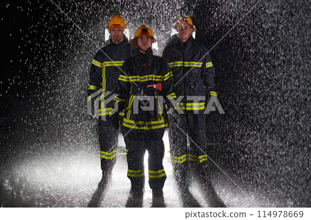 A group of professional firefighters marching through the rainy night on a rescue mission, their determined strides and fearless expressions reflecting their unwavering bravery and unwavering 114978669