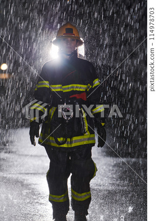 A determined female firefighter in a professional uniform striding through the dangerous, rainy night on a daring rescue mission, showcasing her unwavering bravery and commitment to saving lives. 114978703