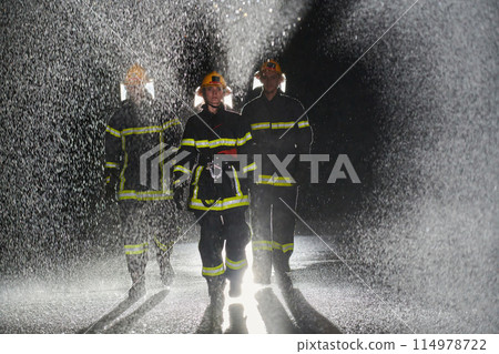 A group of professional firefighters marching through the rainy night on a rescue mission, their determined strides and fearless expressions reflecting their unwavering bravery and unwavering 114978722