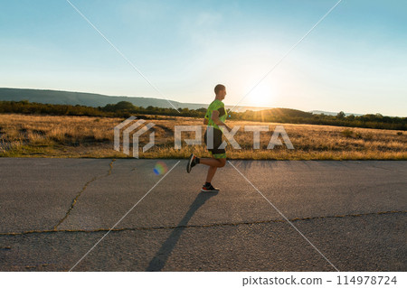Triathlete in professional gear running early in the morning, preparing for a marathon, dedication to sport and readiness to take on the challenges of a marathon.  114978724