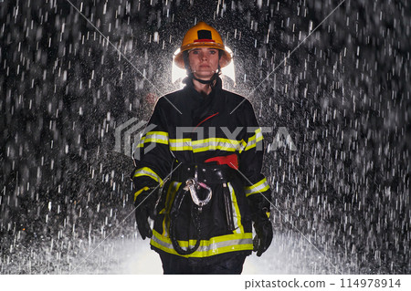 A determined female firefighter in a professional uniform striding through the dangerous, rainy night on a daring rescue mission, showcasing her unwavering bravery and commitment to saving lives. A determined female firefighter in a professional uniform striding through the dangerous, rainy night on a daring rescue mission, showcasing her unwavering bravery and commitment to saving lives. 114978914