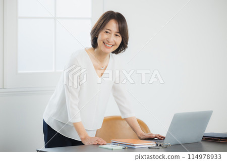 Middle-aged woman working remotely 114978933
