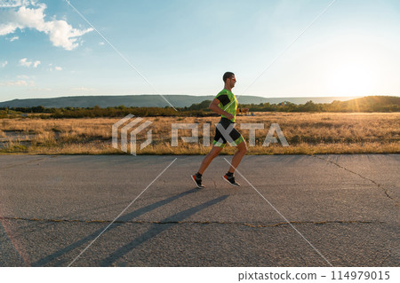 Triathlete in professional gear running early in the morning, preparing for a marathon, dedication to sport and readiness to take on the challenges of a marathon. Triathlete in professional gear running early in the morning, preparing for a marathon, dedication to sport and readiness to take on the challenges of a marathon. 114979015