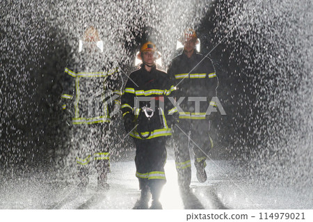 A group of professional firefighters marching through the rainy night on a rescue mission, their determined strides and fearless expressions reflecting their unwavering bravery and unwavering 114979021