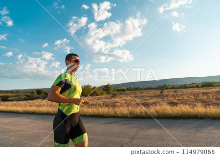 Triathlete in professional gear running early in the morning, preparing for a marathon, dedication to sport and readiness to take on the challenges of a marathon.  114979068